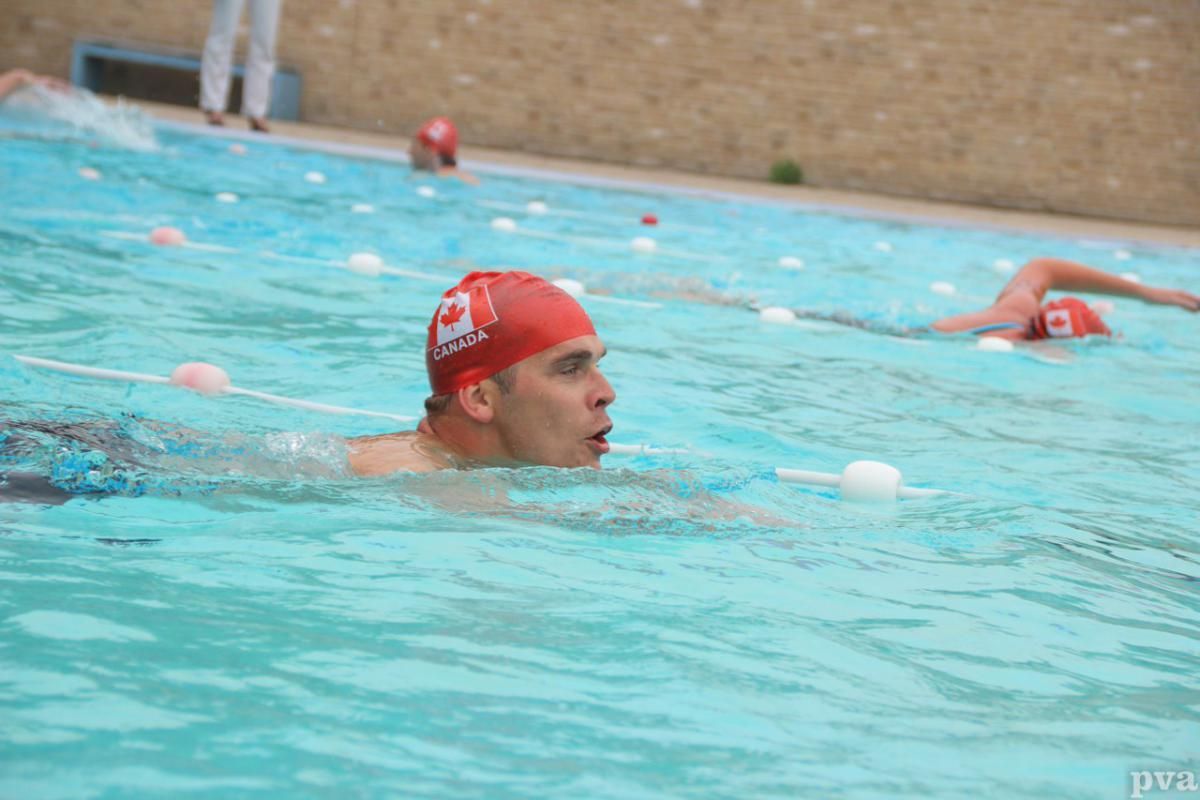 Een man met een rode badmuts zwemt in een zwembad.