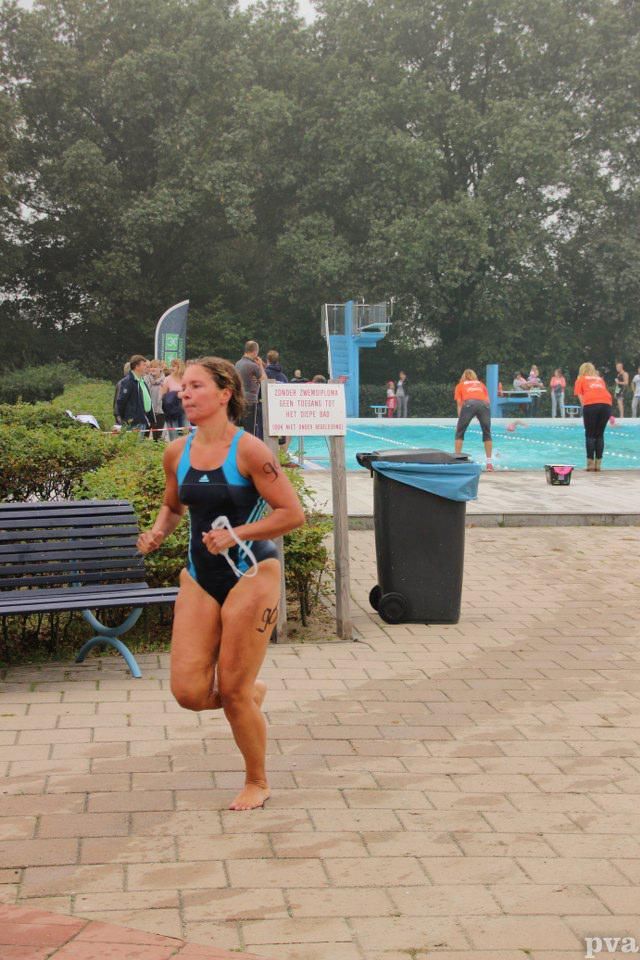 Een vrouw in badpak rent voor een zwembad.