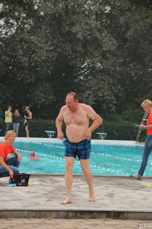 Een man zonder shirt staat voor een zwembad.