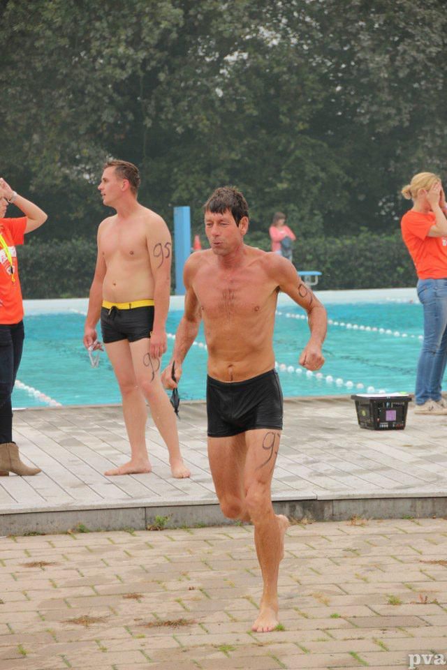 Een man zonder shirt rent voor een zwembad.