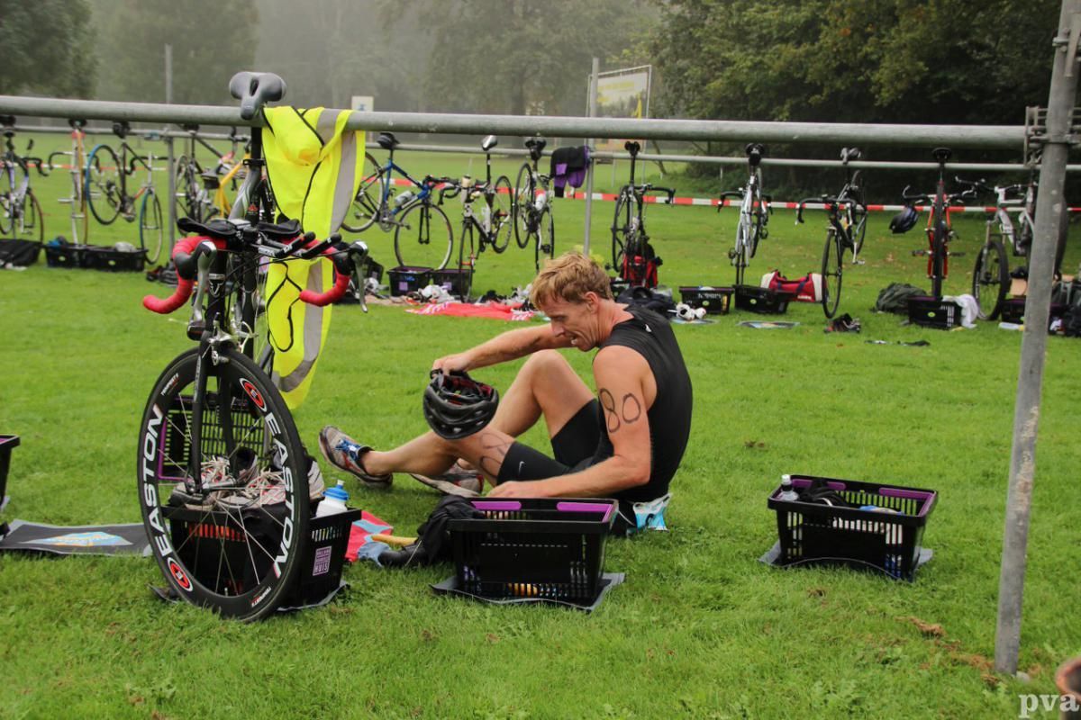Een man zit op het gras naast een fiets