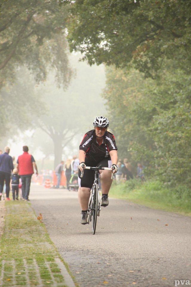 Een man fietst over een pad in de mist.