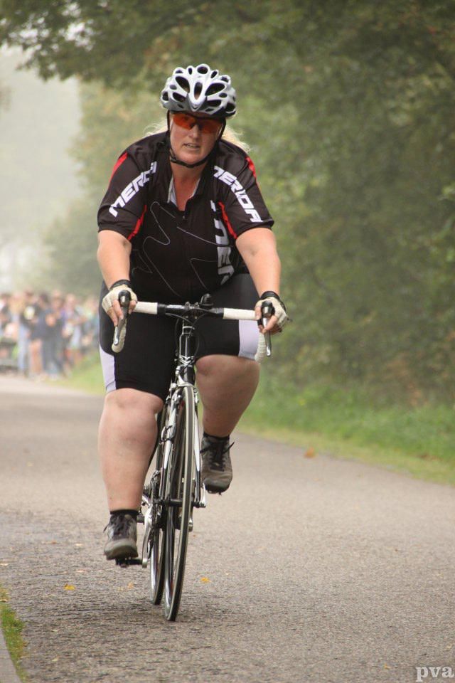 Een vrouw met een helm op fietst over de weg.