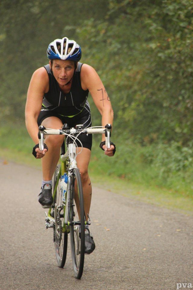 Een vrouw met een helm op fietst over de weg.