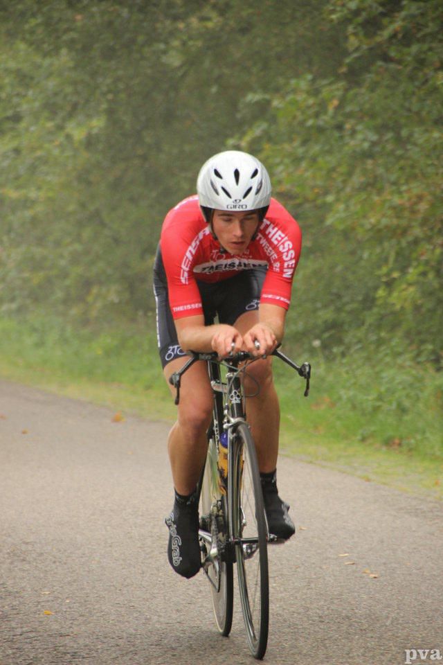 Een man met een helm rijdt op een fiets over de weg.