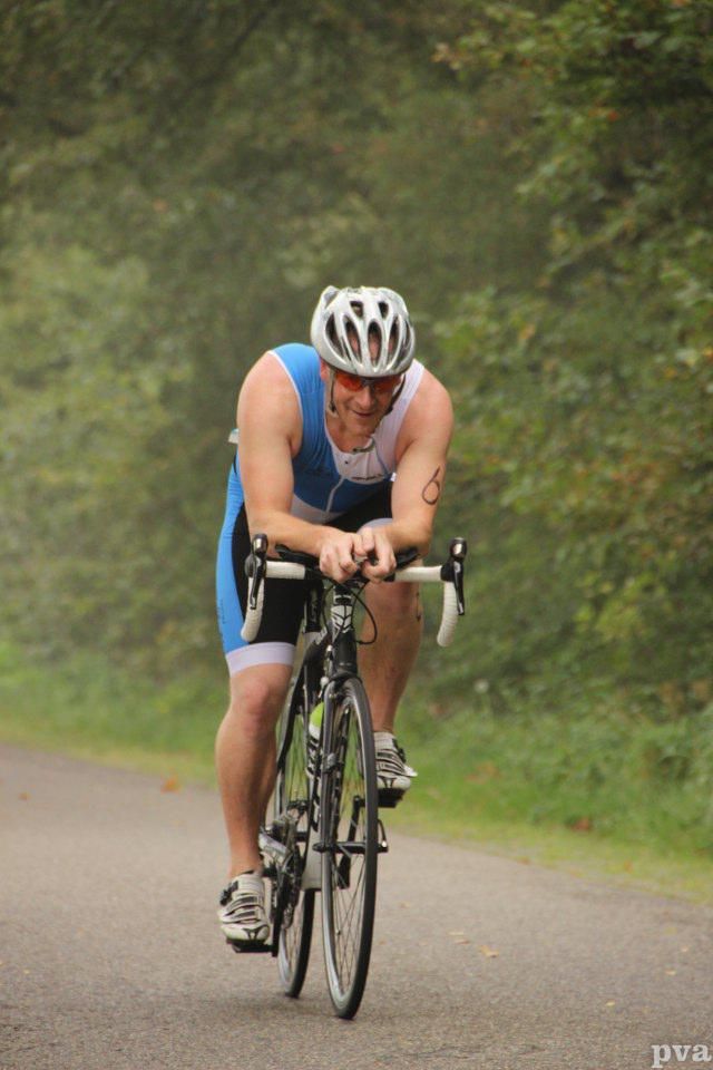 Een man met een helm rijdt op een fiets over de weg.