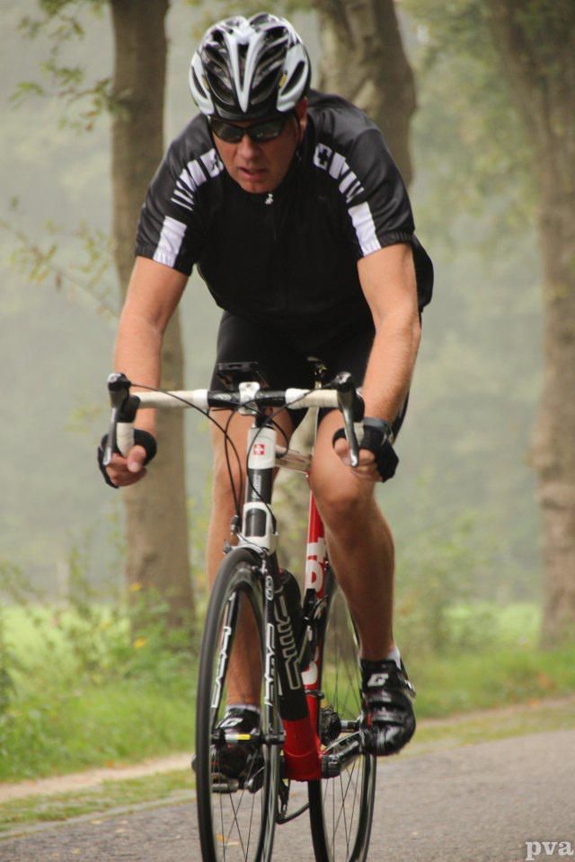 Triathlon Eibergen. Een man met een helm rijdt op een fiets op een weg