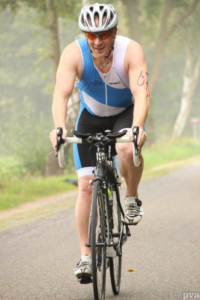 Triathlon Eibergen. Een man met een helm rijdt op een fiets op de weg.
