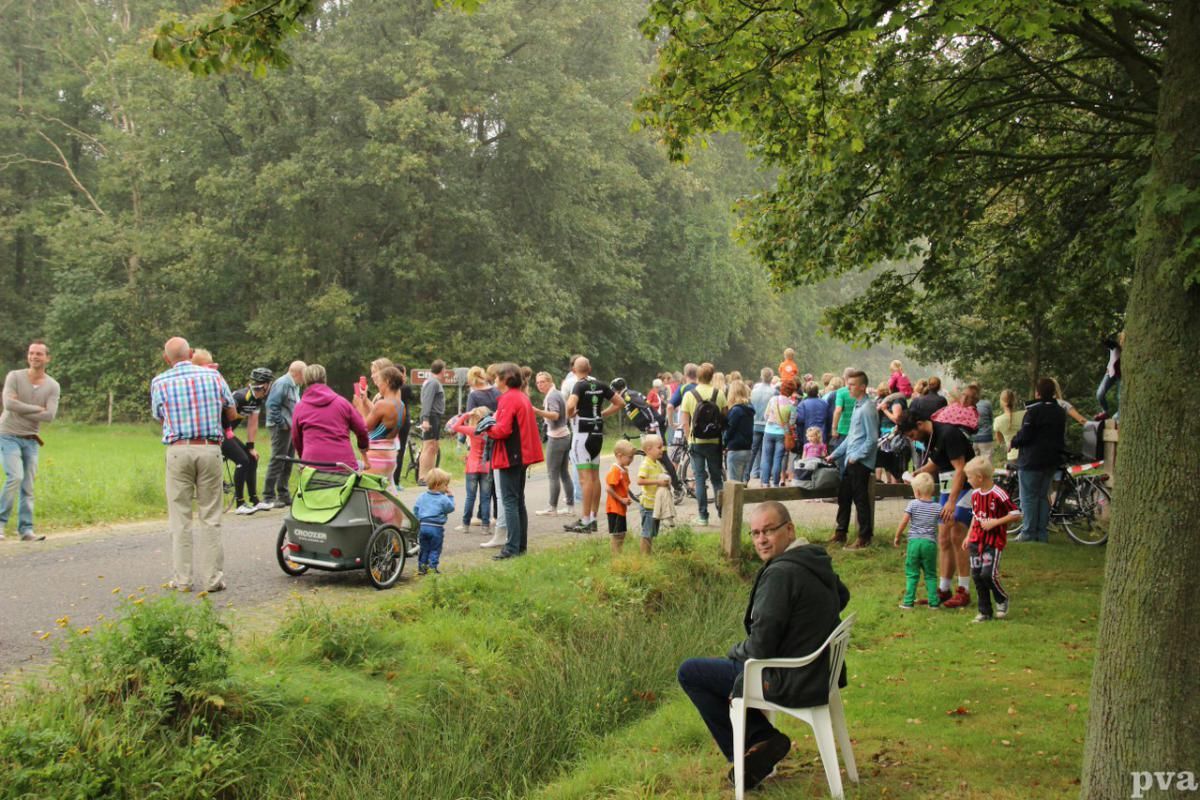 Triathlon Eibergen. Een man zit op een stoel voor een groep mensen in een park.