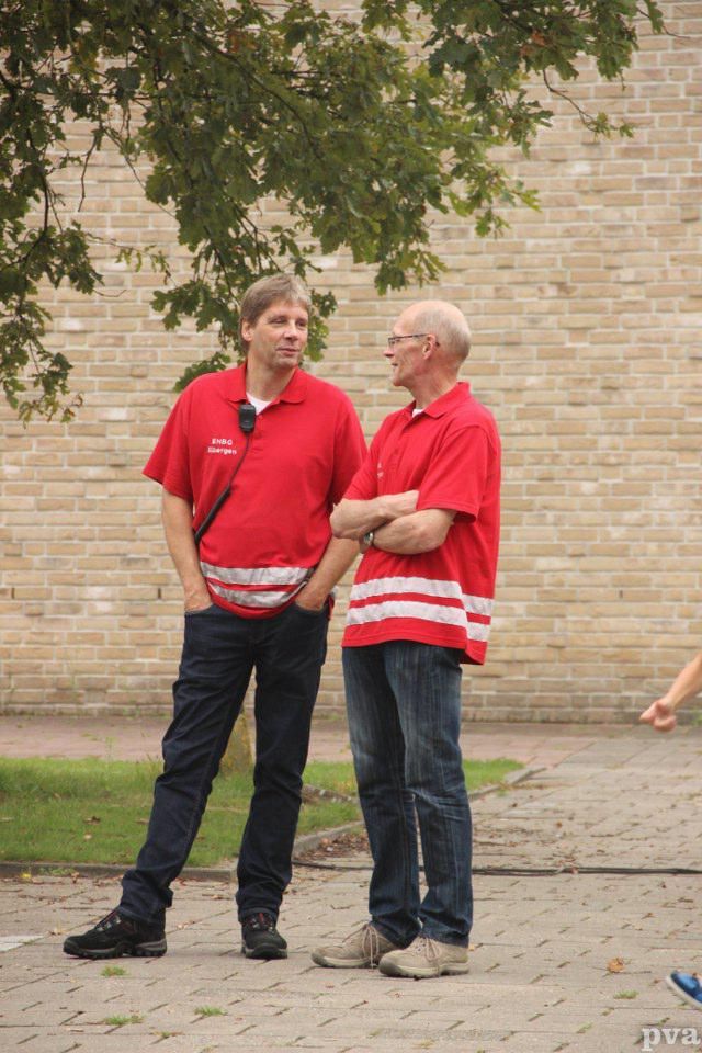 Triathlon Eibergen. Twee mannen in rode shirts staan ​​naast elkaar op de stoep.