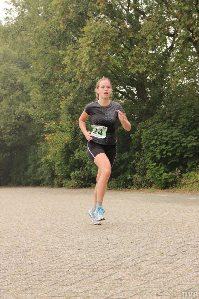 Triathlon Eibergen. Een vrouw rent op een stenen weg in een park.