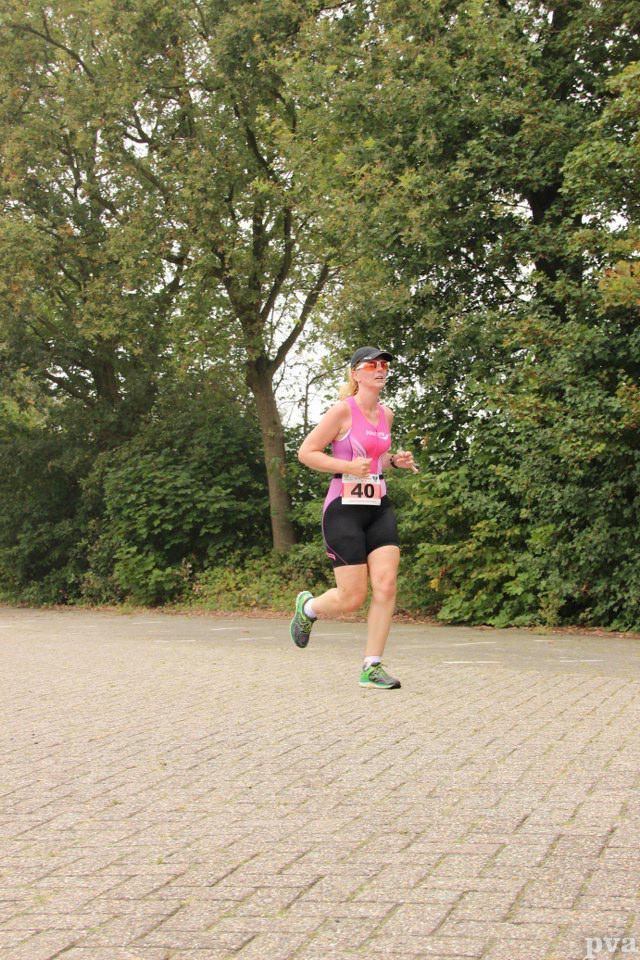 Triathlon Eibergen. Een vrouw rent over een stenen weg in een park.