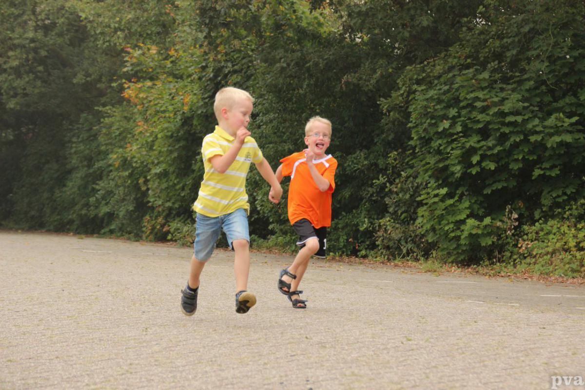 Triathlon Eibergen. Twee jonge jongens rennen hand in hand over de weg.