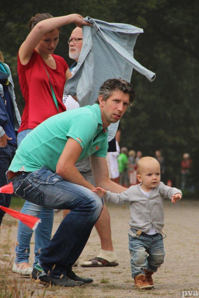 Triathlon Eibergen. Een man knielt naast een baby die loopt.