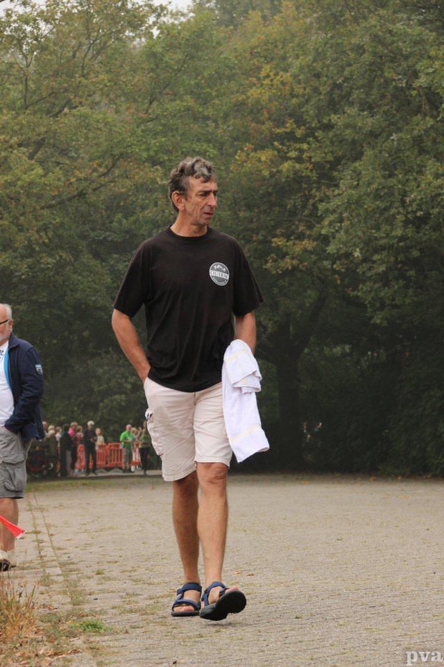 Triathlon Eibergen. Een man in een zwart shirt en een witte korte broek loopt over straat.