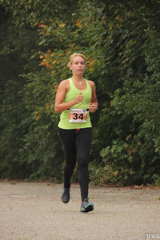 Triathlon Eibergen. Een vrouw in een groen tanktopje en zwarte leggings rent een race.