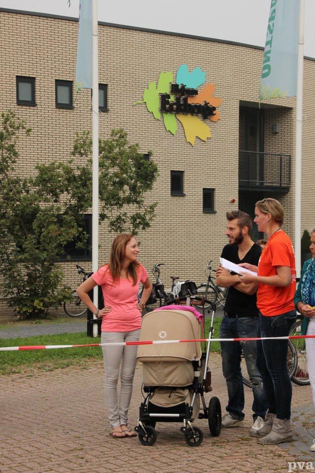 Triathlon Eibergen. Een groep mensen die met een kinderwagen voor een gebouw staan