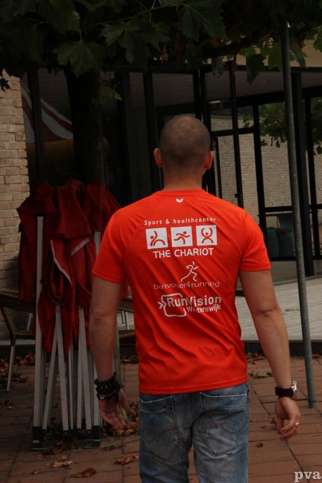 Een man met een oranje shirt met de tekst 'de strijdwagen'