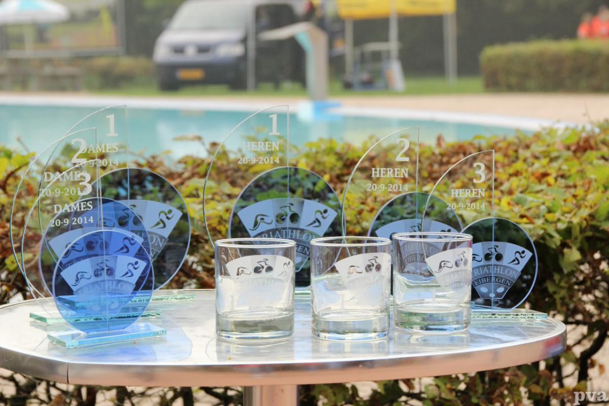 Een tafel met glazen en trofeeën erop voor een zwembad.