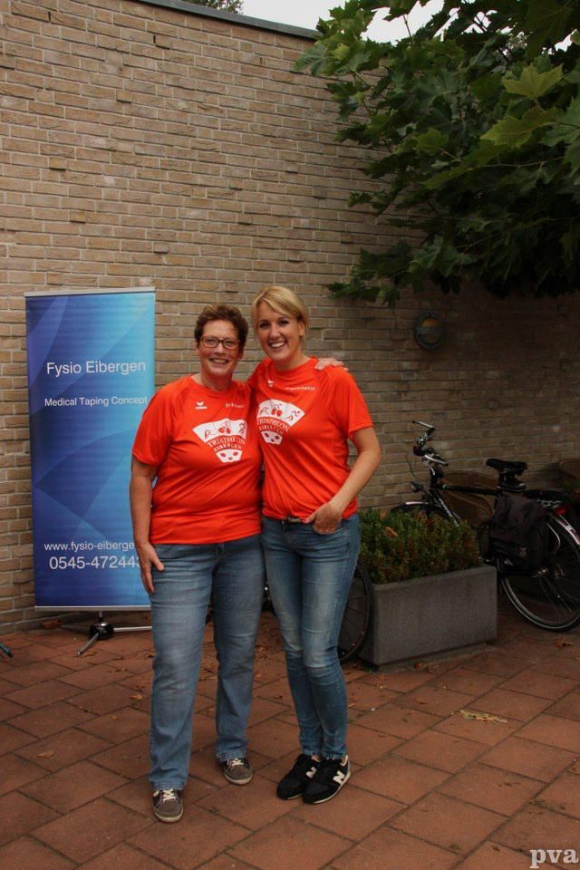 Twee vrouwen poseren voor een foto voor een bakstenen muur.