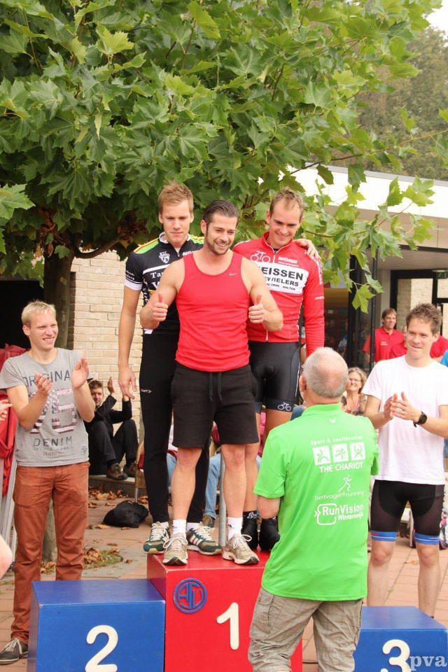 Een man in een groen shirt staat op een podium met andere mannen