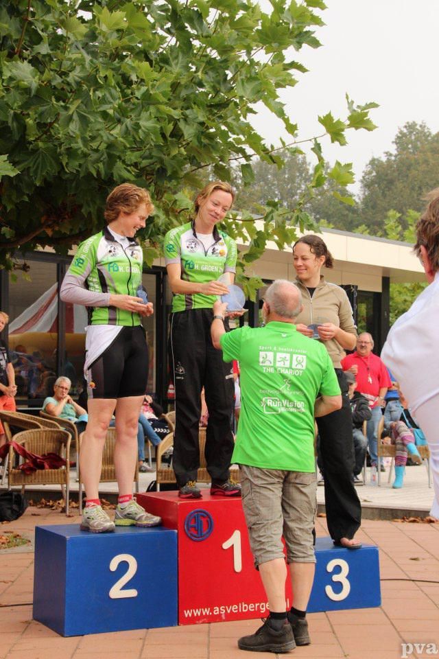 Een man in een groen shirt staat op een podium met de nummers 2 en 3