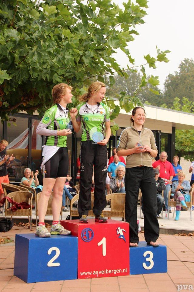 Drie vrouwen staan ​​op een podium met de nummers 2, 1 en 3