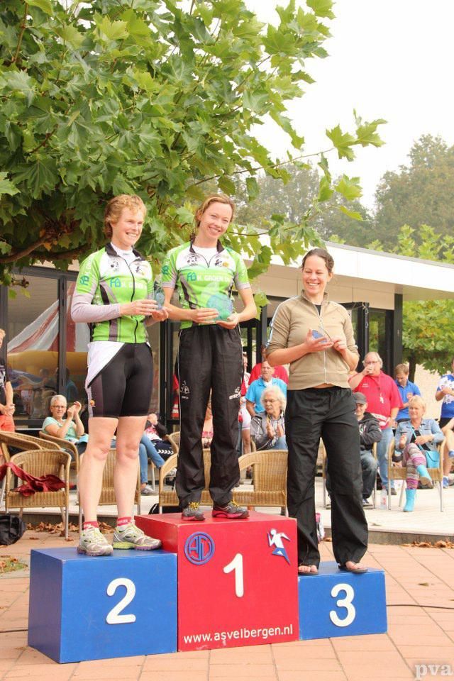 Drie vrouwen staan ​​op een podium met de nummers 2, 1 en 3