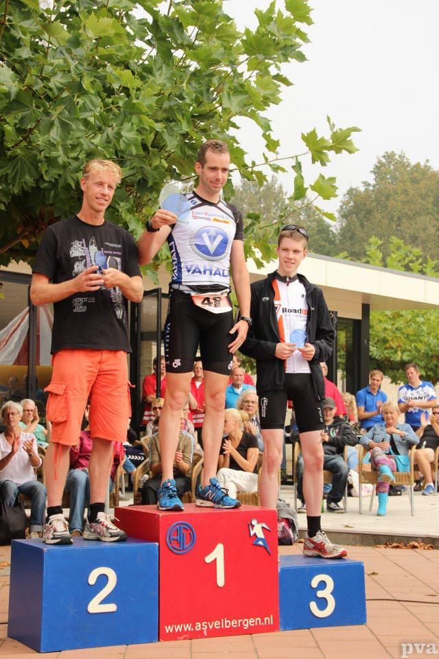 Drie mannen staan ​​op een podium met de nummers 1, 2 en 3 erop