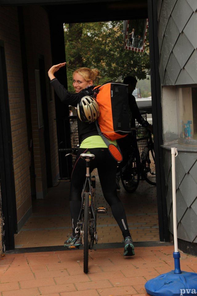Een vrouw fietst door een deuropening.
