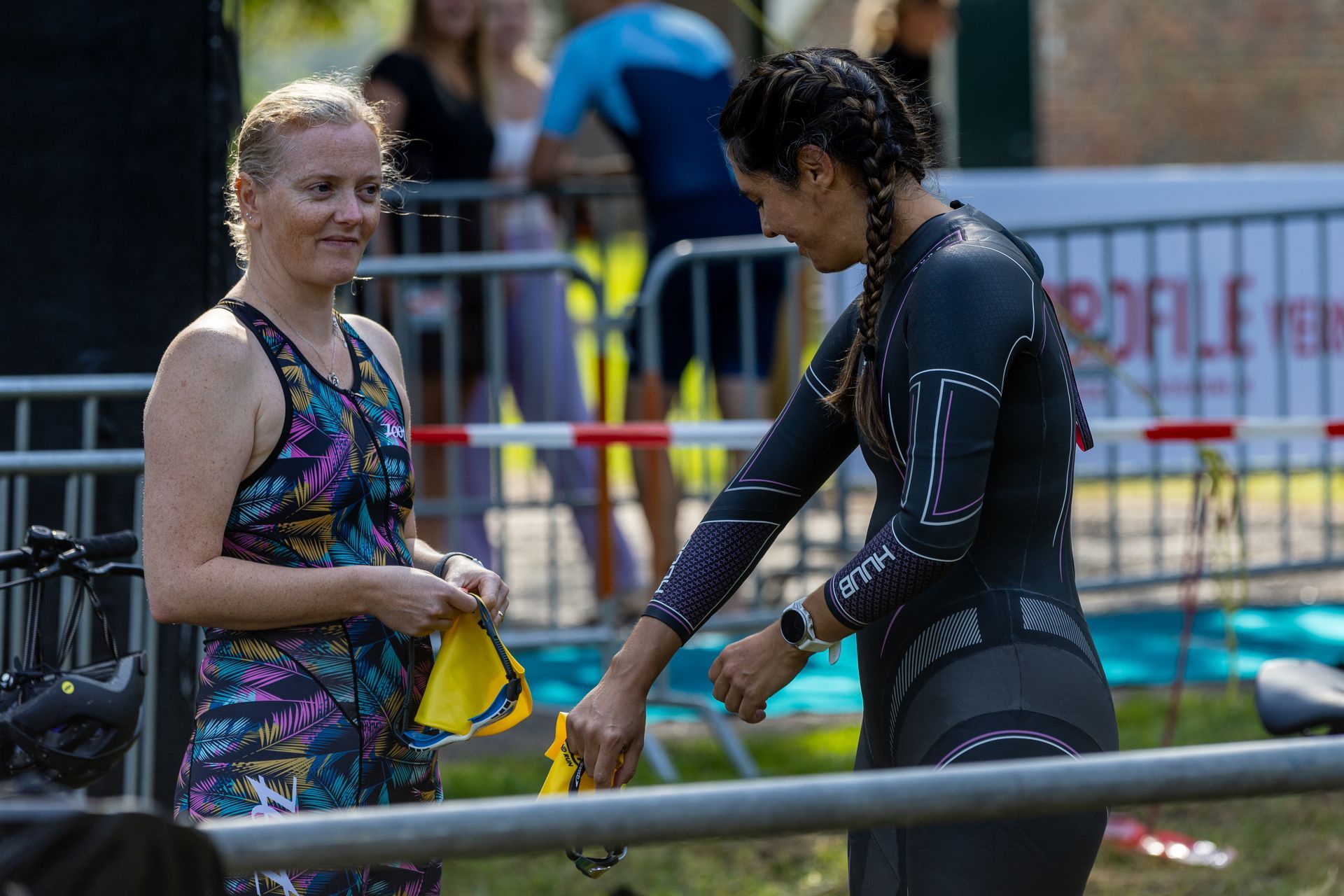 Twee vrouwen in wetsuits praten met elkaar.