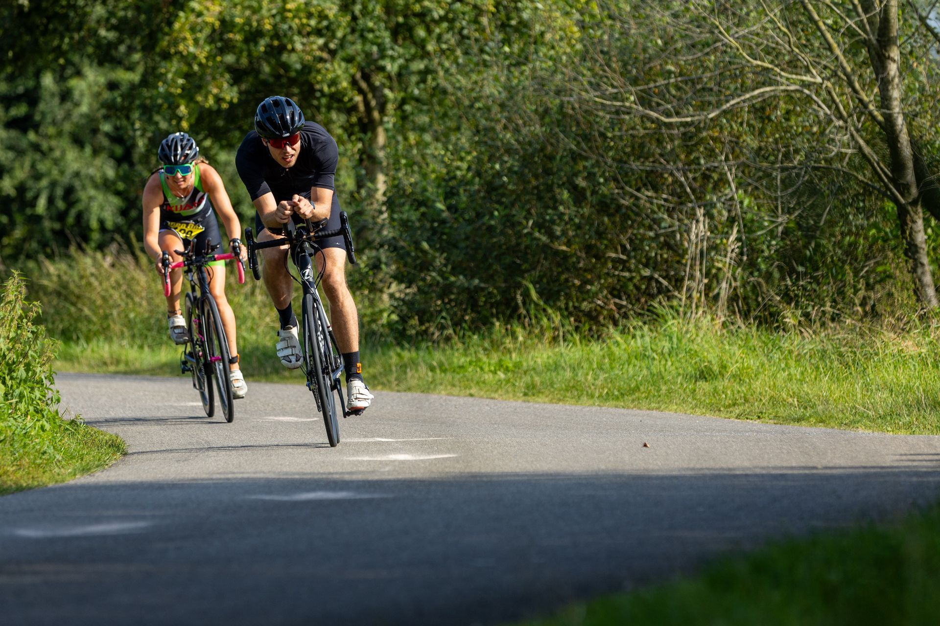 Een man en een vrouw fietsen over een weg.