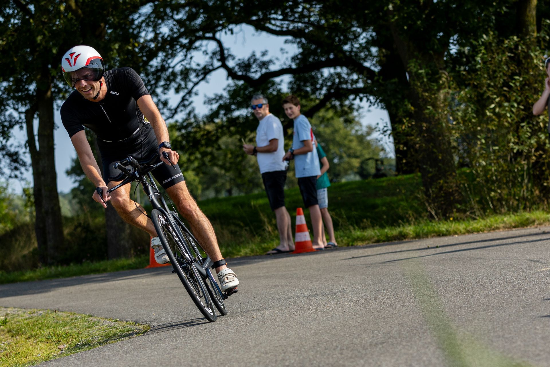 Een man met een helm rijdt op een fiets over de weg.