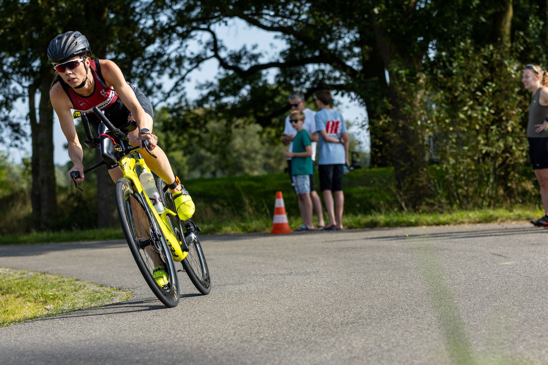 Een vrouw rijdt op een gele fiets over de weg.