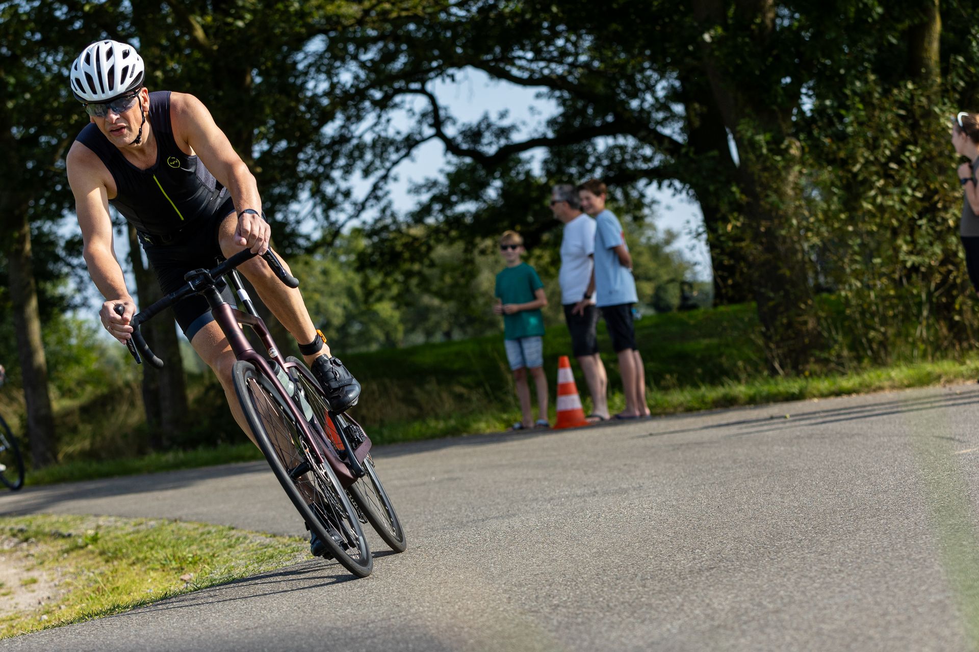 Een man met een helm rijdt op een fiets over de weg.