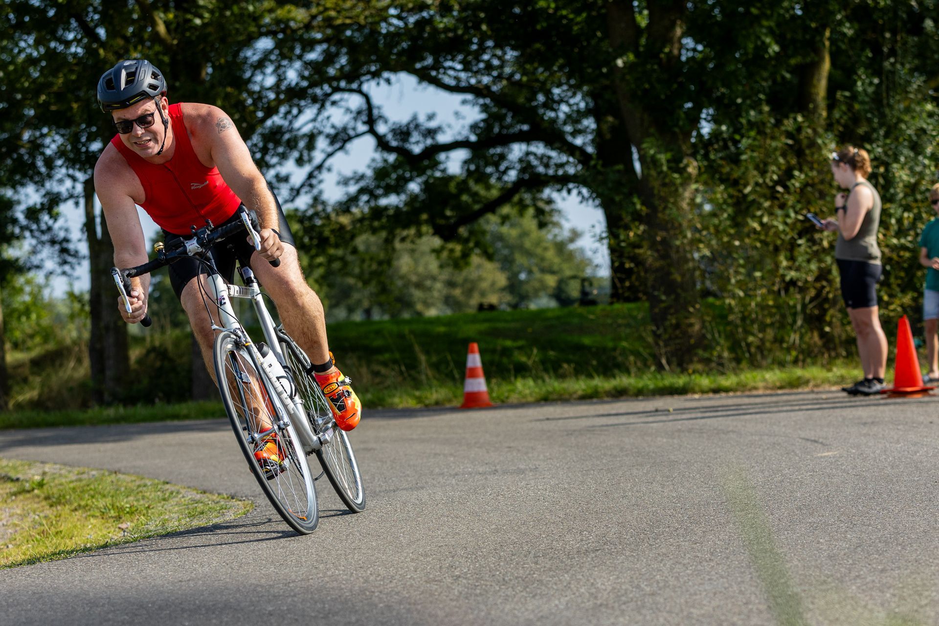 Een man in een rood tanktopje fietst over een weg.