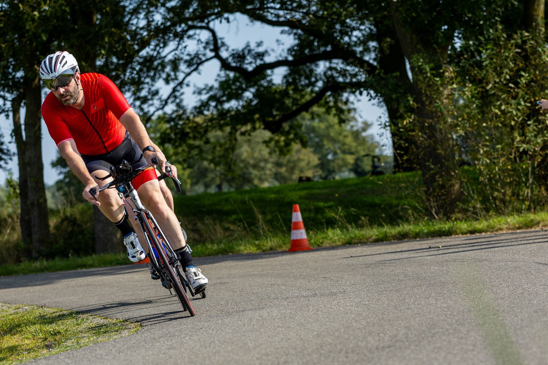 Een man in een rood shirt fietst over een weg.