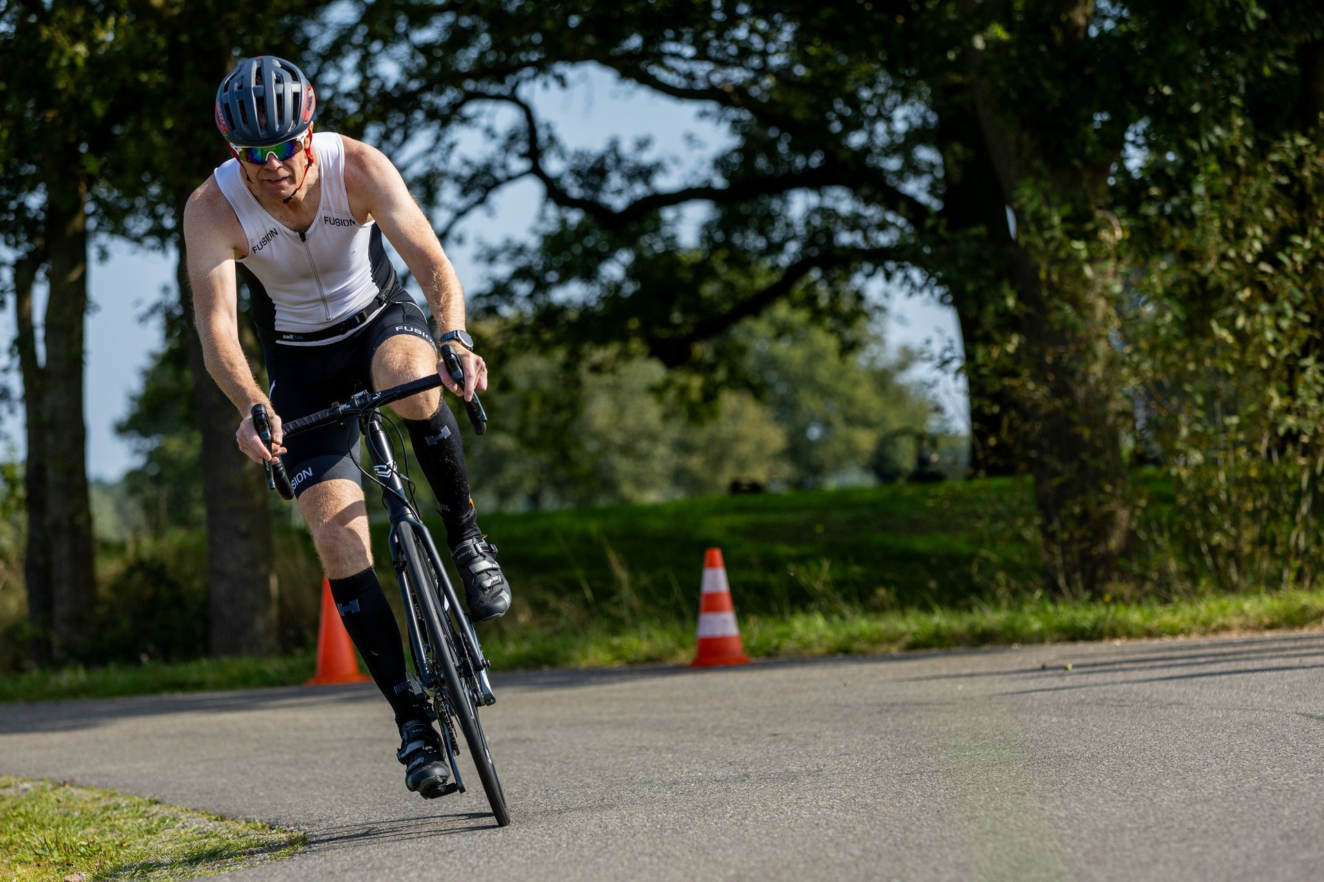 Een man fietst over een weg naast een verkeerskegel.