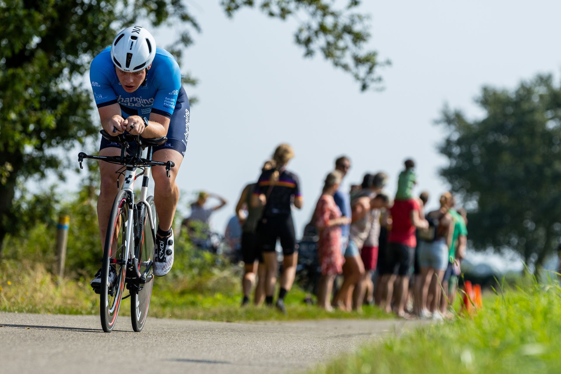 Een man fietst over een weg voor een menigte mensen.
