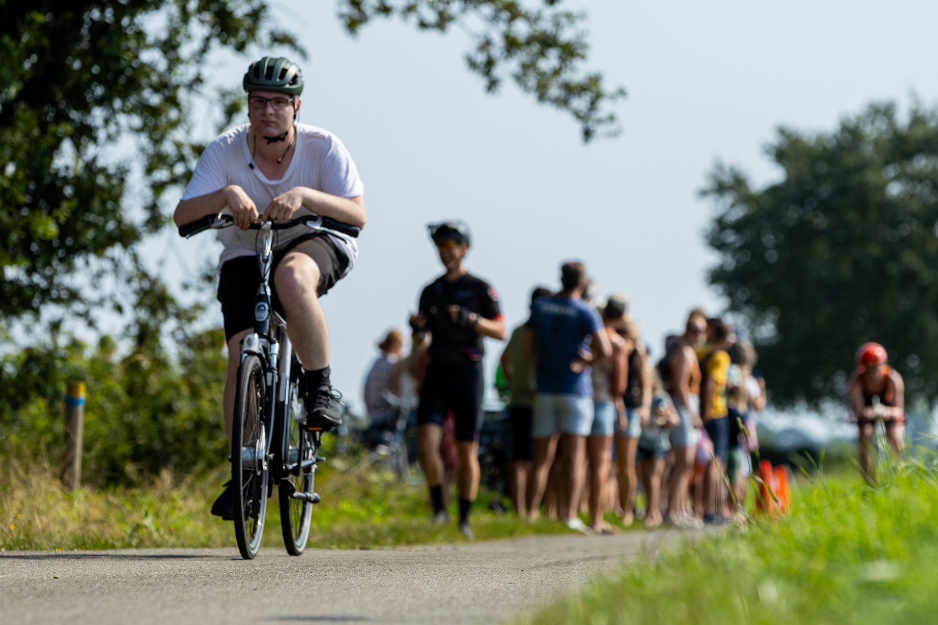 Een man fietst over een weg voor een menigte mensen.