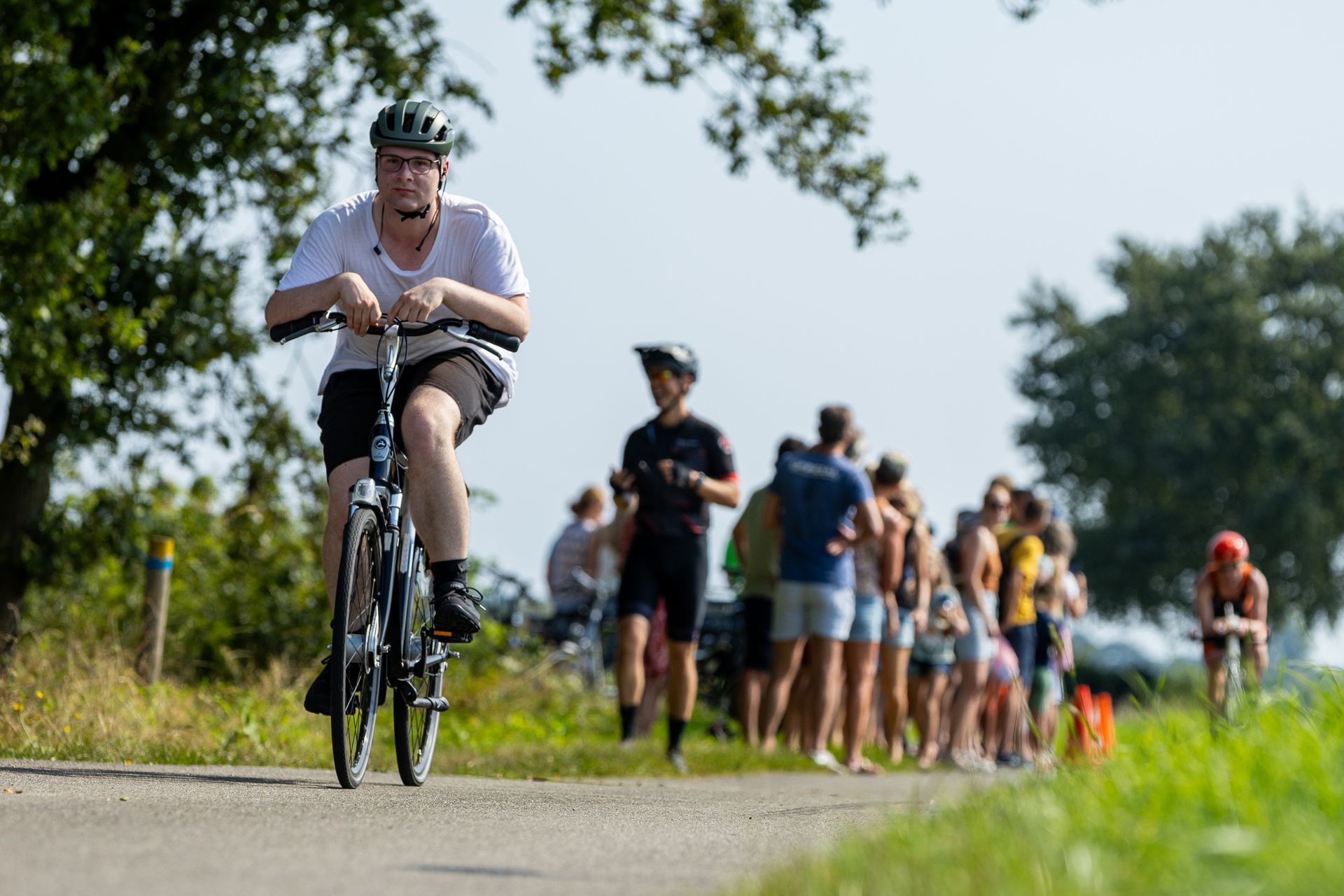Een man fietst over een weg naast een groep mensen.