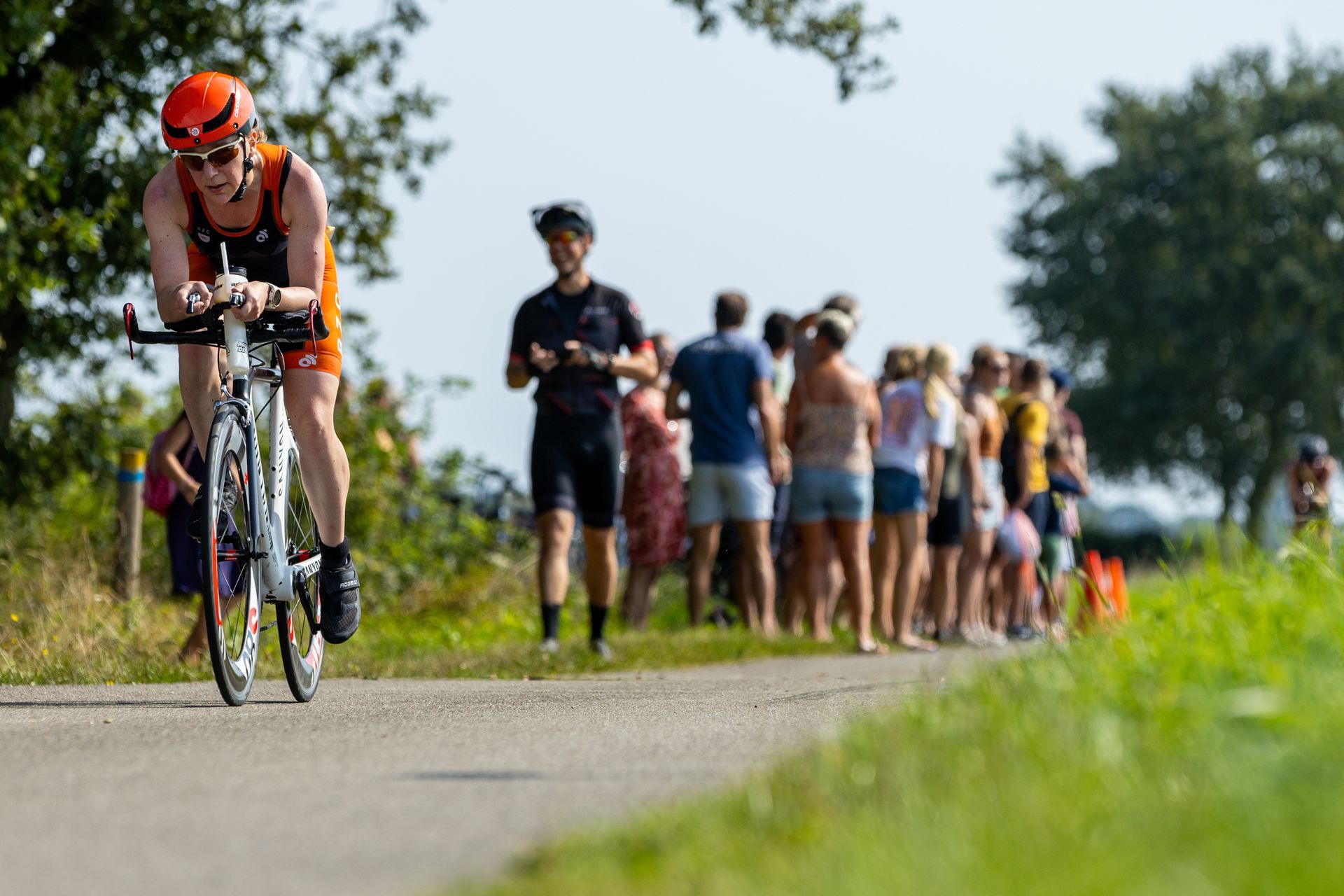 Een man fietst over een weg voor een menigte mensen.