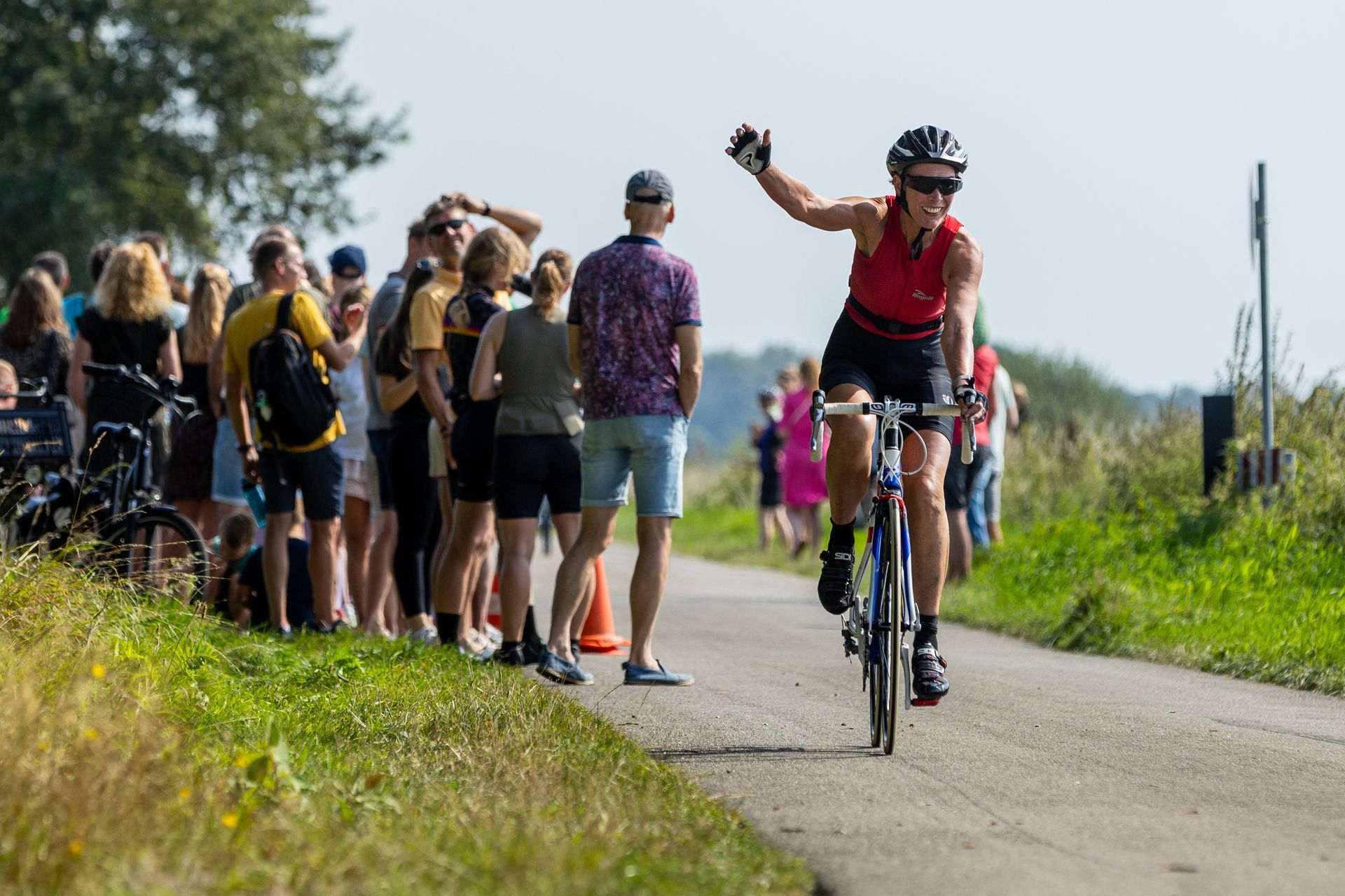 Een vrouw fietst over een weg terwijl de menigte toekijkt.