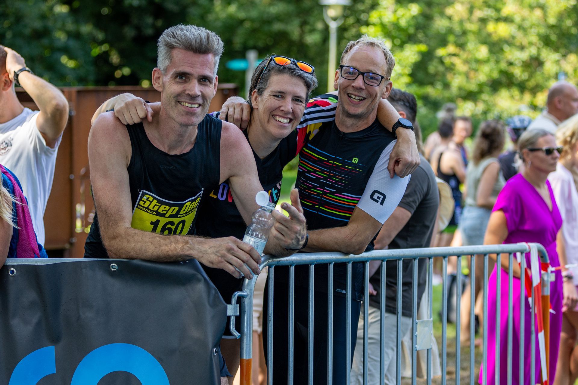 Een groep mensen poseert voor een foto achter een hek bij een race.