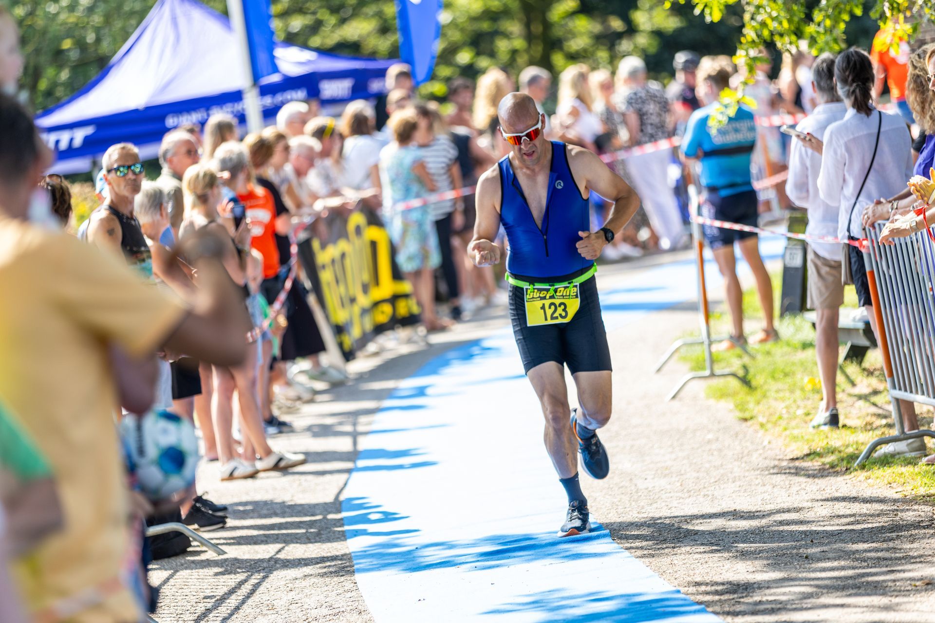 Een man rent een marathon voor een grote groep mensen.