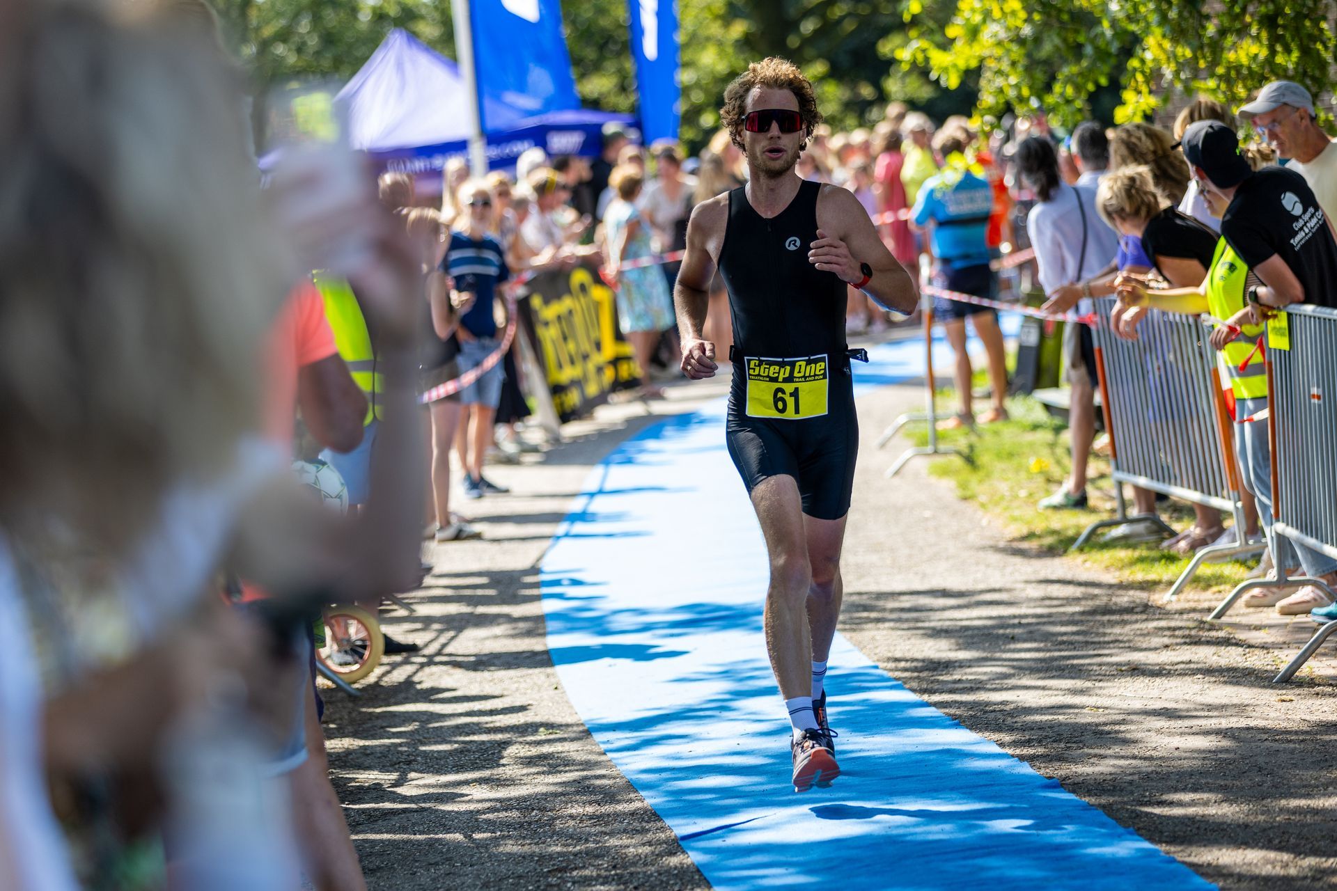 Een man rent een marathon voor een grote groep mensen.