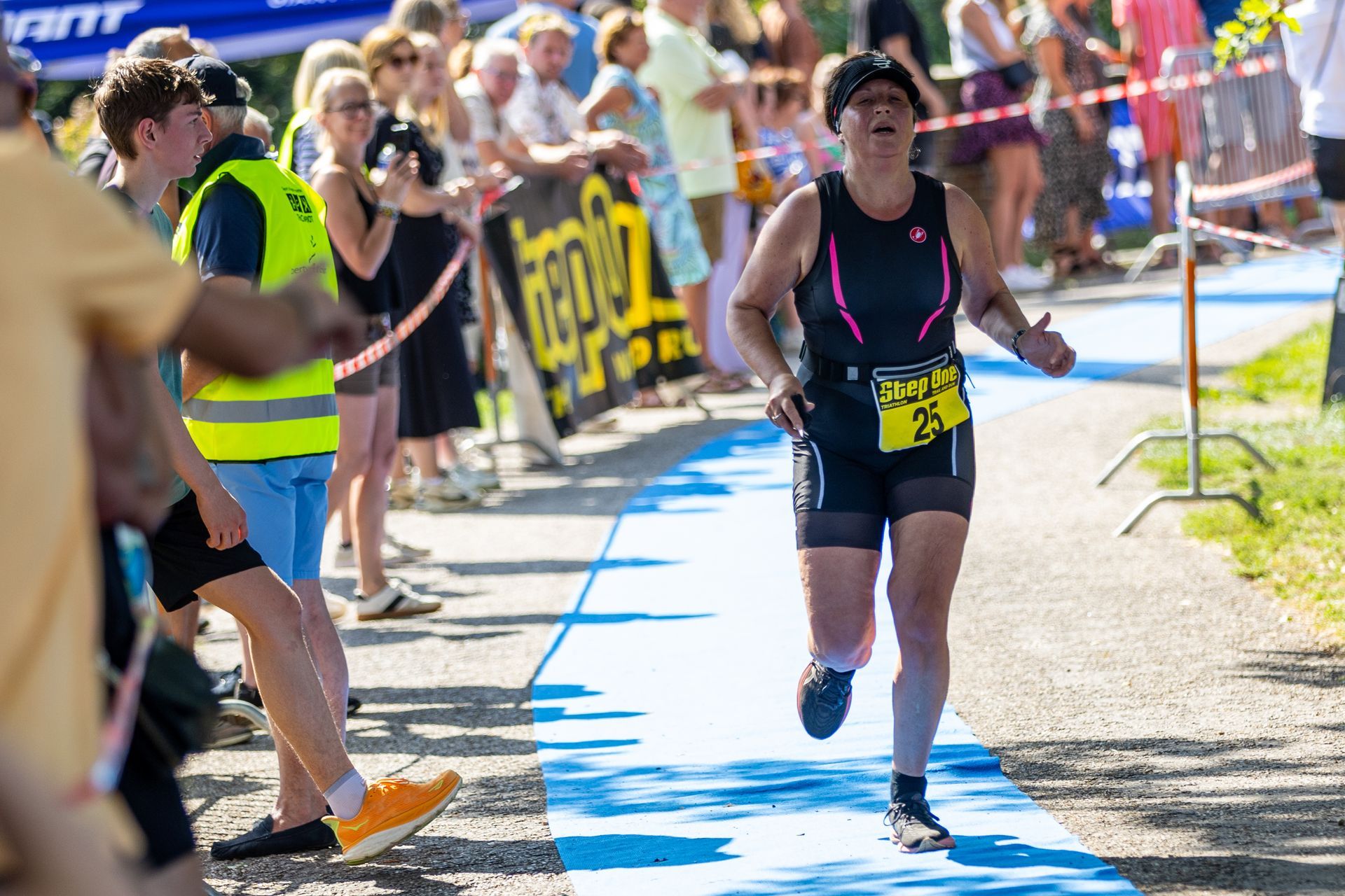 Een vrouw rent een marathon voor een grote groep mensen.