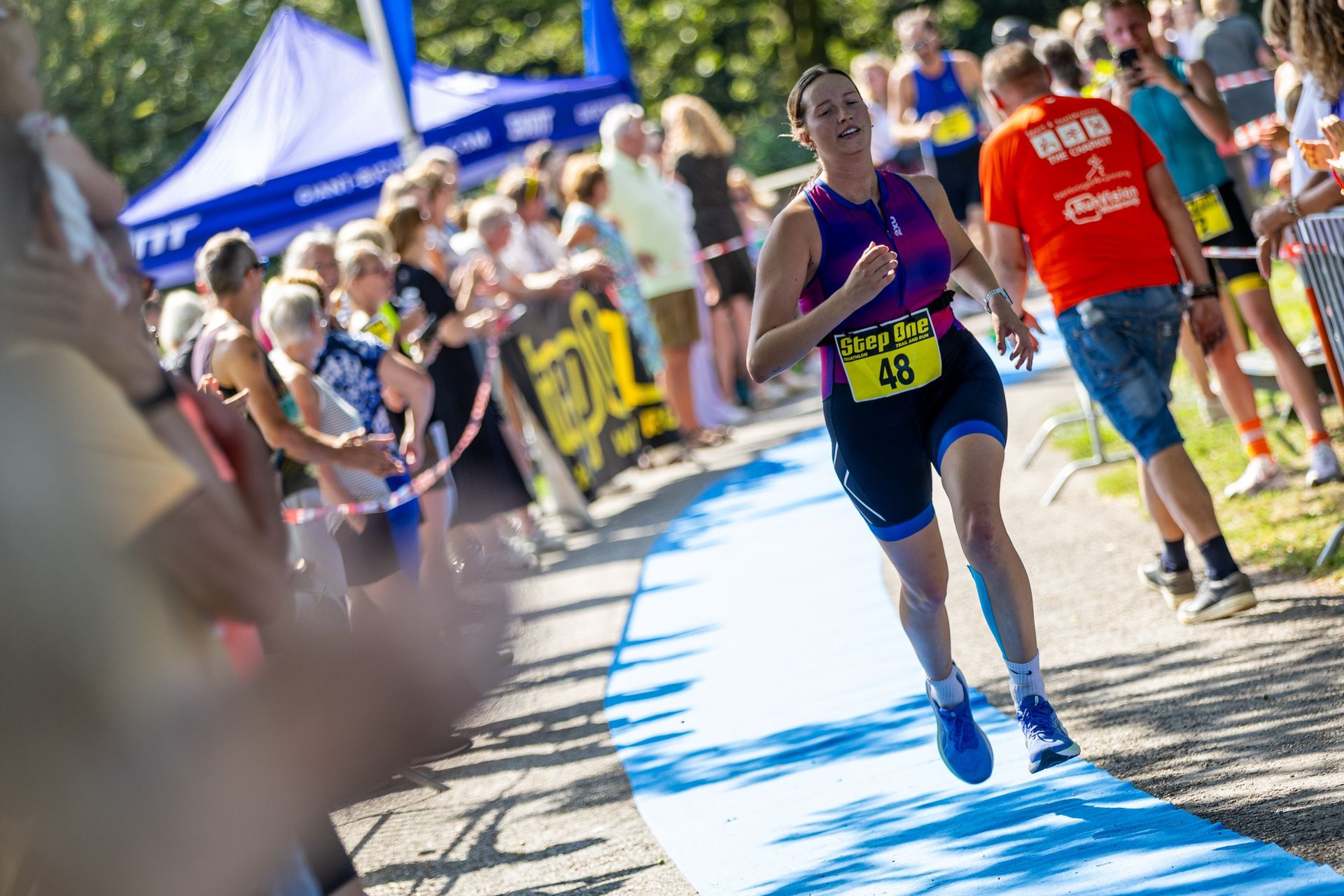 Een vrouw rent op een blauwe loper tijdens een triatlon.
