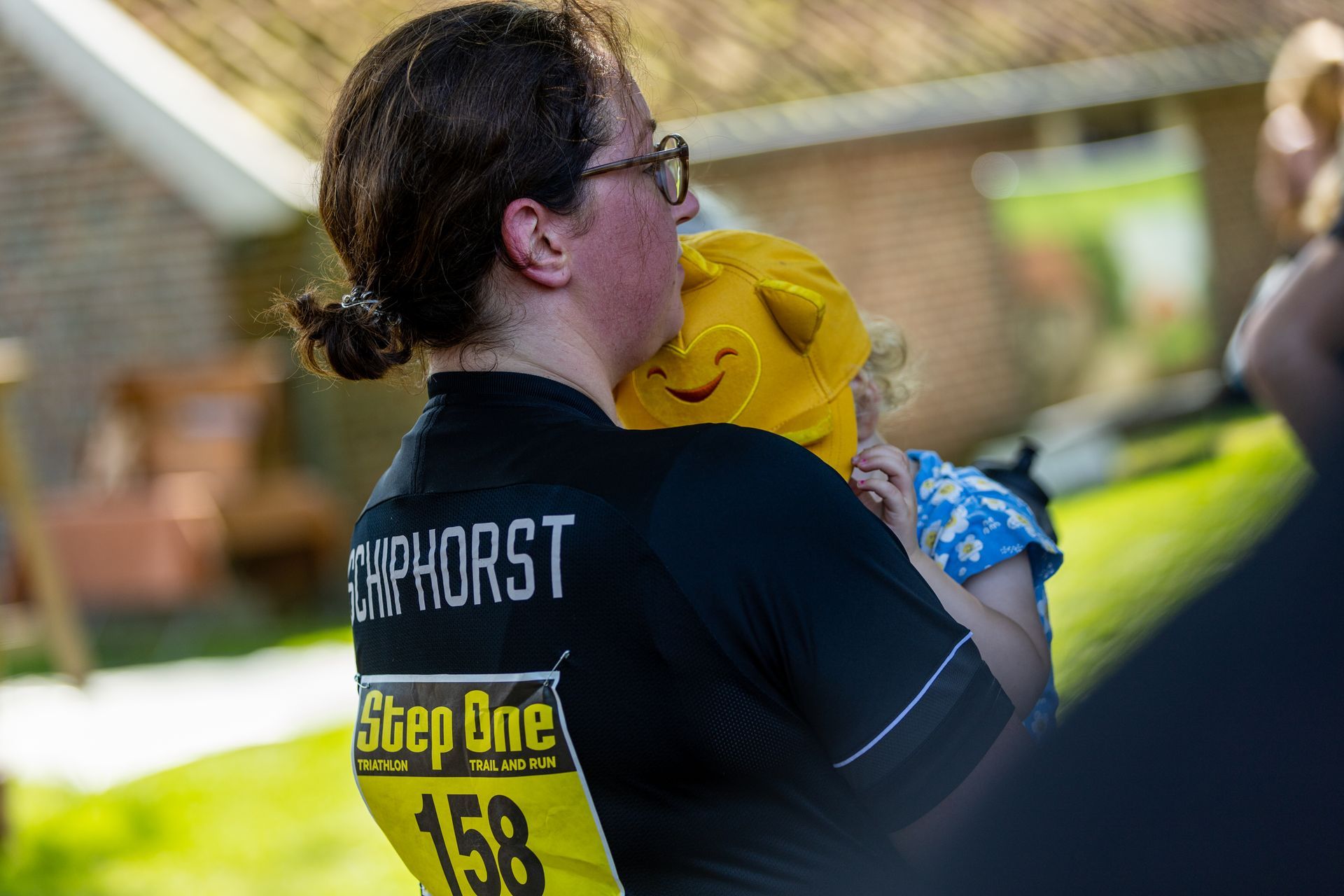 Een vrouw draagt ​​een step one 158 shirt en houdt een baby vast.