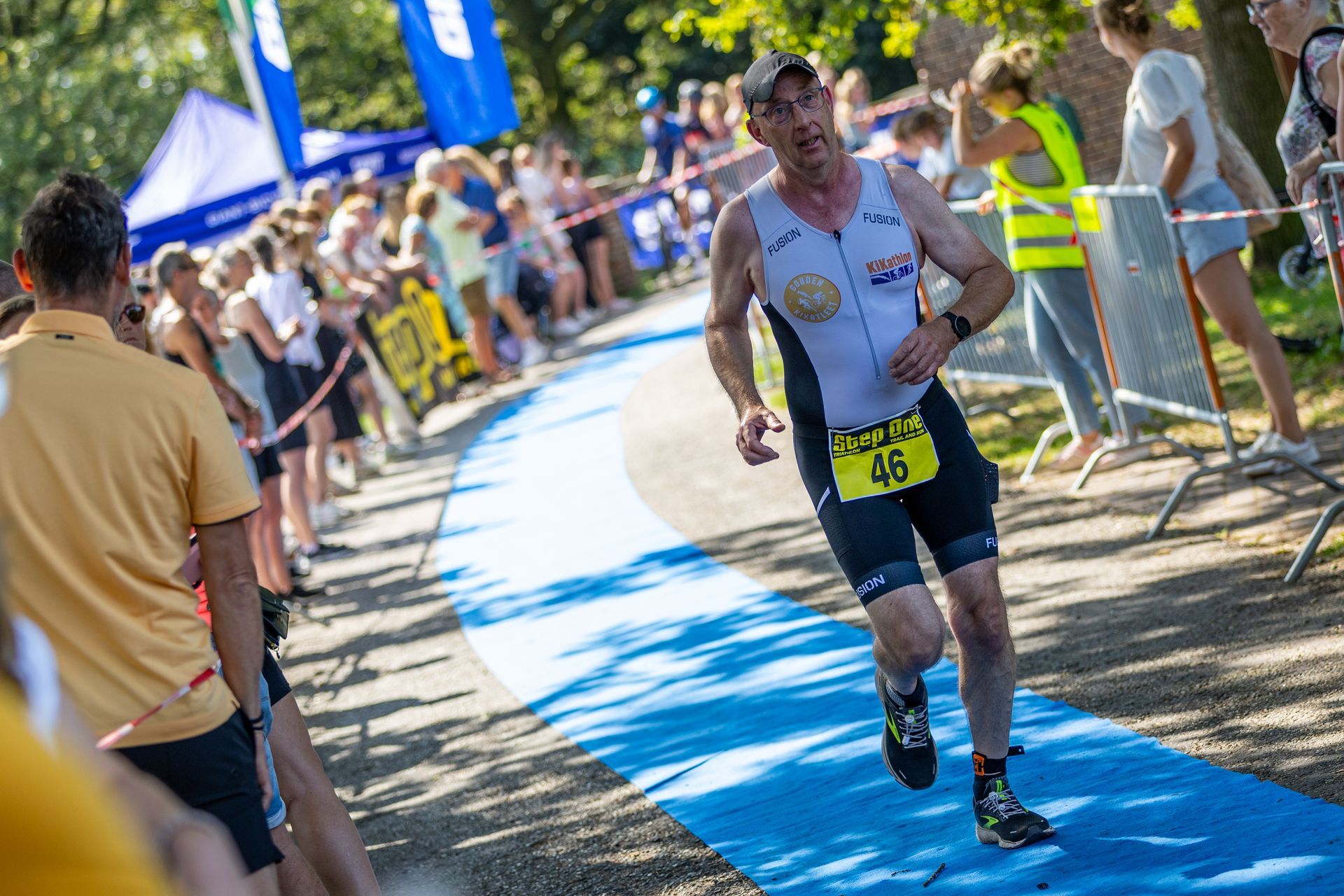 Een man rent op een blauwe loper tijdens een triatlon.